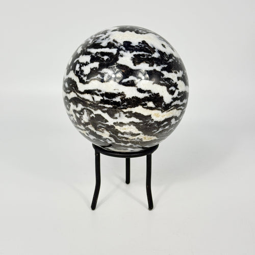 Zebra marble patterned sphere on a black metal stand against a white background