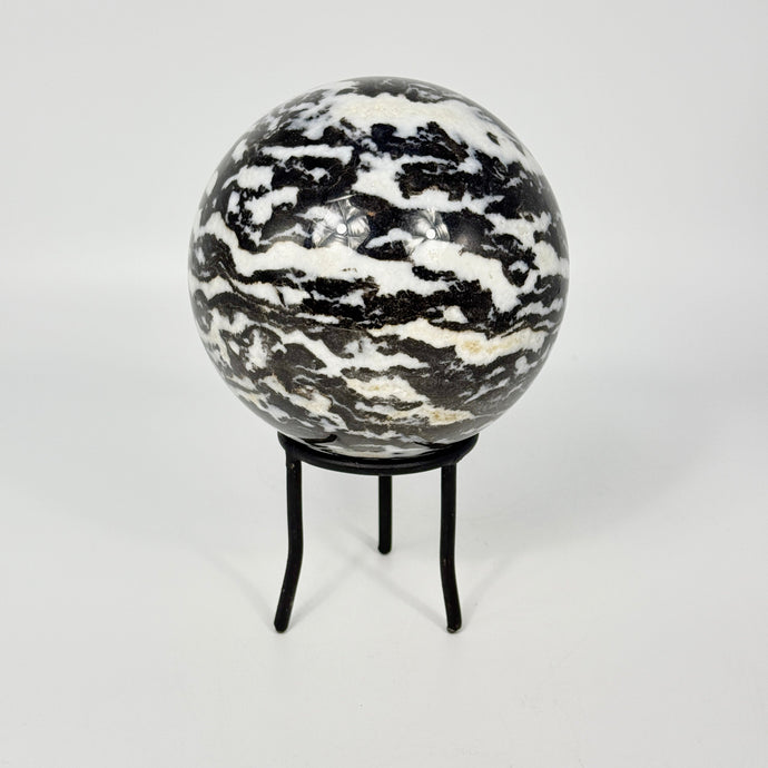 Zebra marble patterned sphere on a black metal stand against a white background