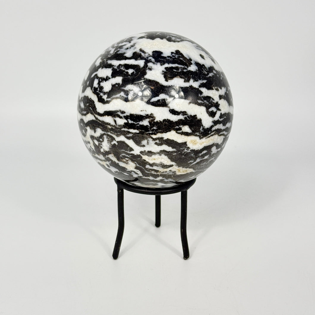 Zebra marble patterned sphere on a black metal stand against a white background