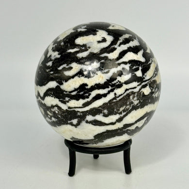 Black and white striped Zebra Marble sphere on a stand against a white background