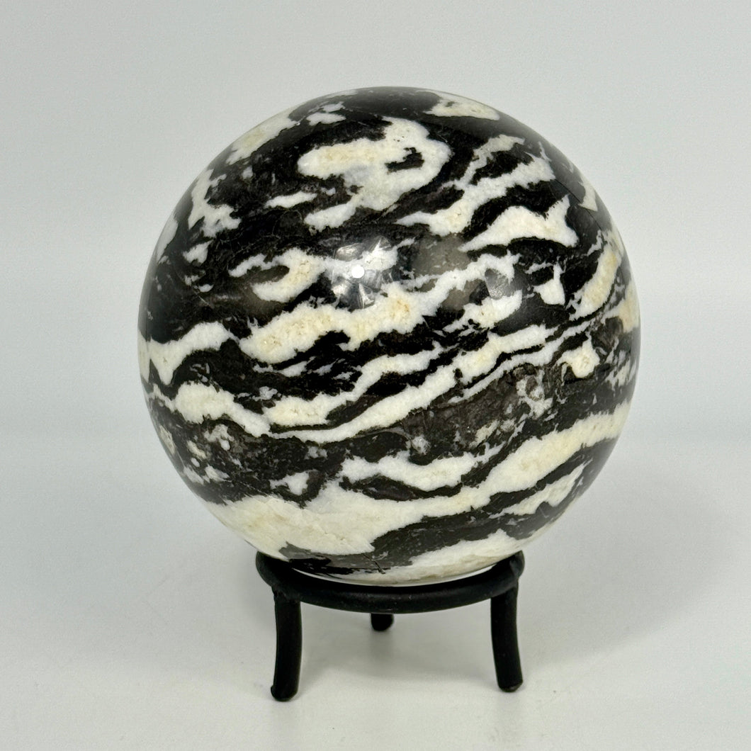 Black and white striped Zebra Marble sphere on a stand against a white background