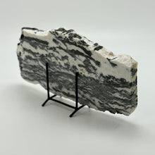 Load image into Gallery viewer, Zebra marble slab with black veining on a stand against a white background
